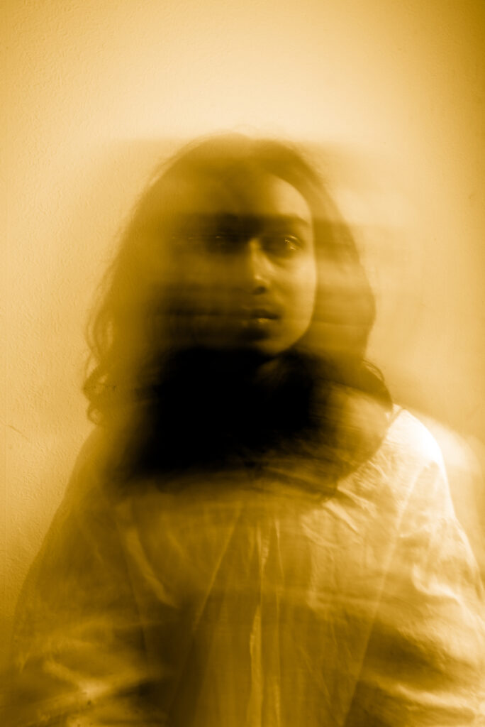 A person is captured in a motion blur, creating a ghostly effect, against a yellow-tinted background.