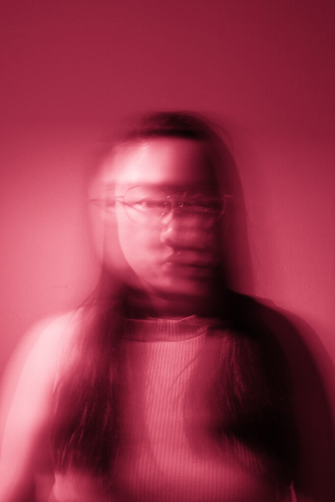 A person is captured in a motion blur, creating a ghostly effect, against a red-tinted background.