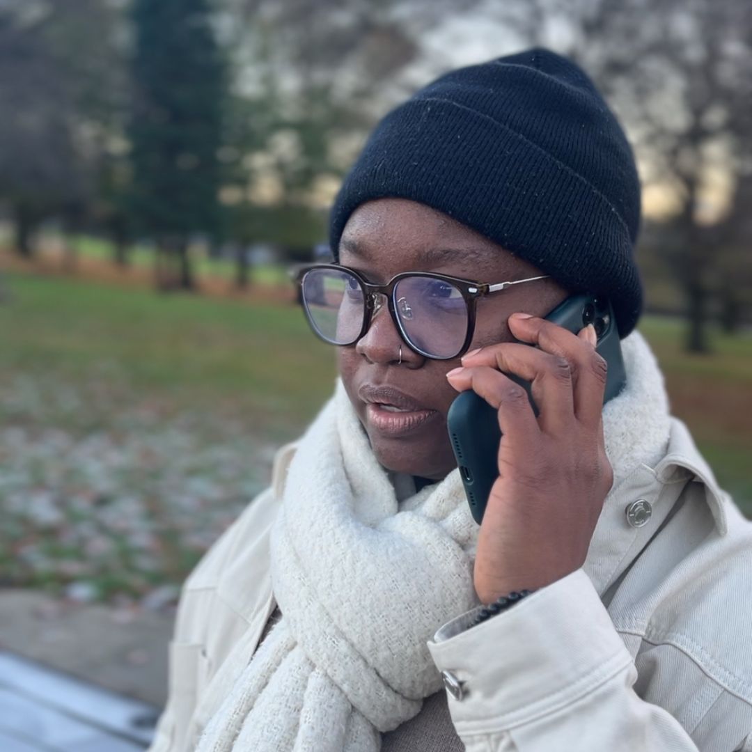 A community member outside in a park phoning LGBT Helpline Scotland