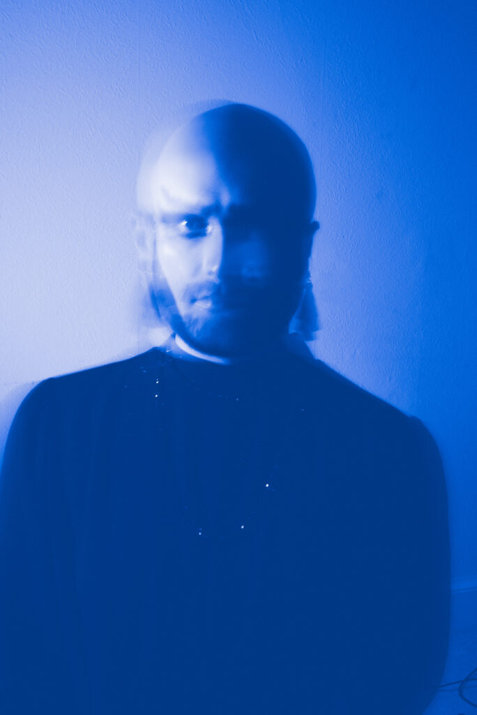 A person is captured in a motion blur, creating a ghostly effect, against a blue-tinted background.