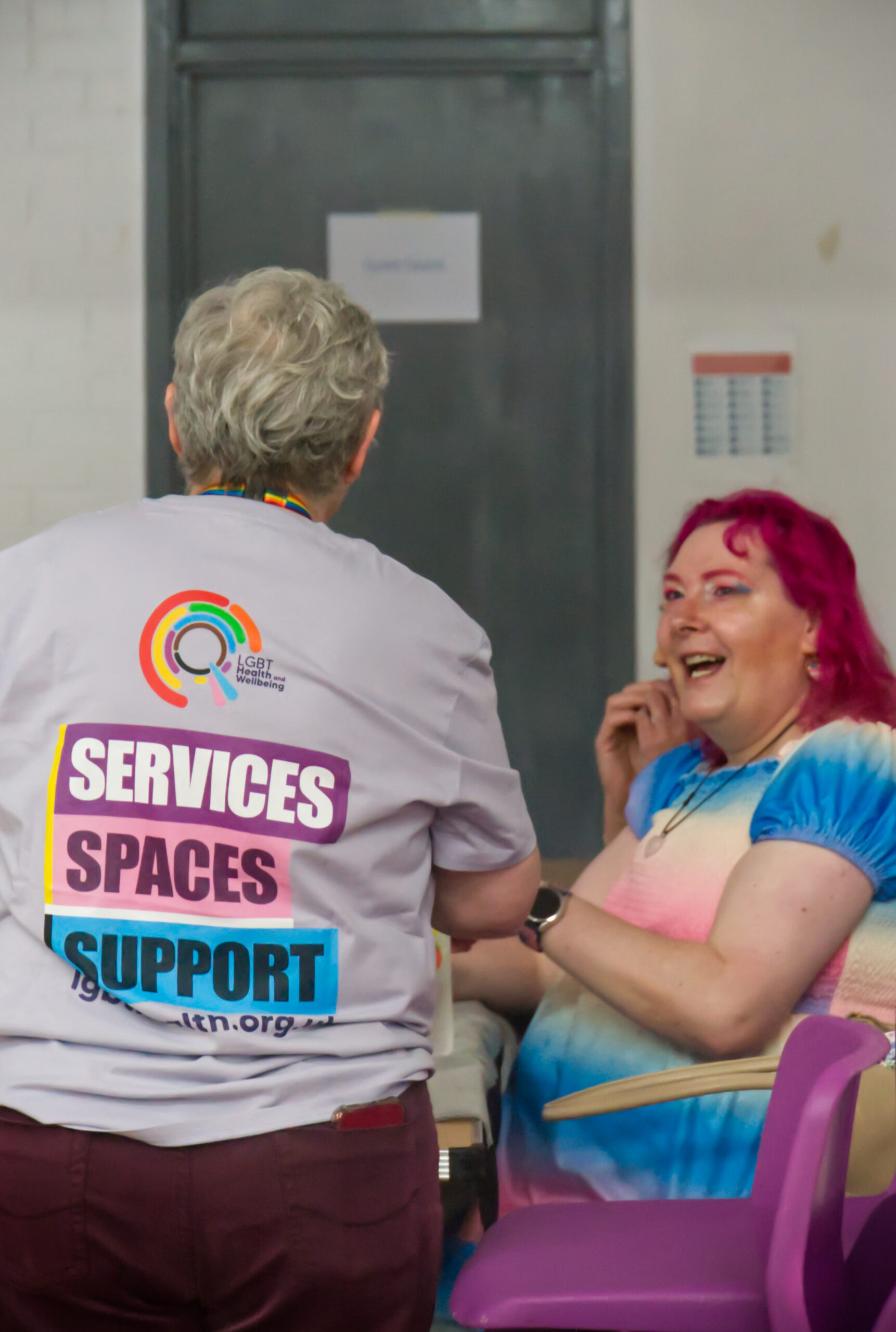 A member of staff talking to a community member at event hosted by LGBT Health and Wellbeing