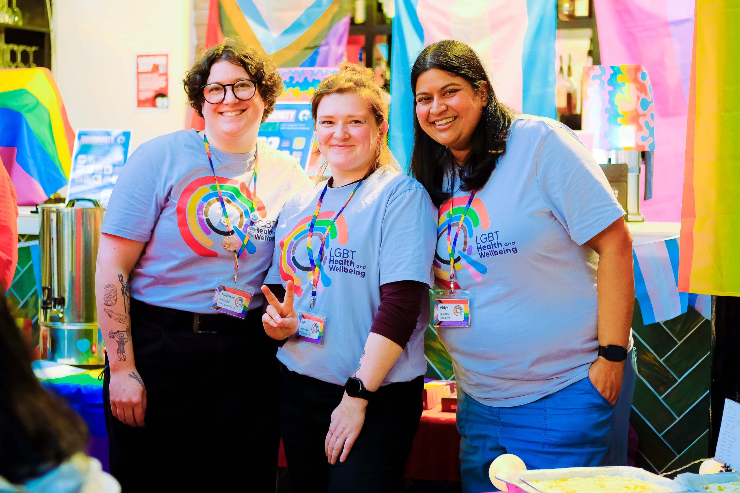 A group of 3 volunteers wearing LGBT Health and Wellbeing t-shirts