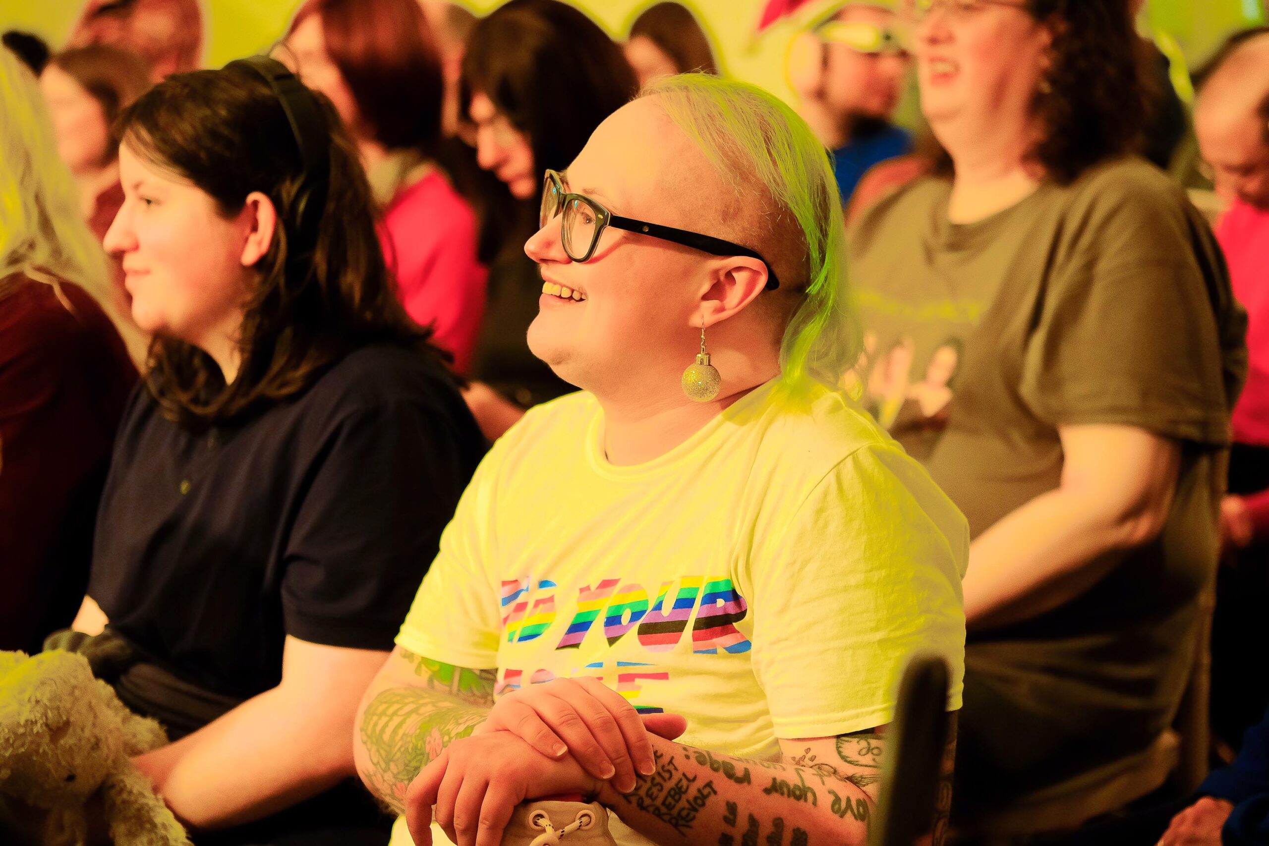 A community member laughing whilst enjoying performances at an event hosted by LGBT Health and Wellbeing