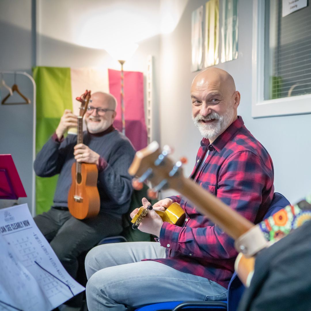 2 members of the community group Rainbow Ukes enjoying a ukulele session