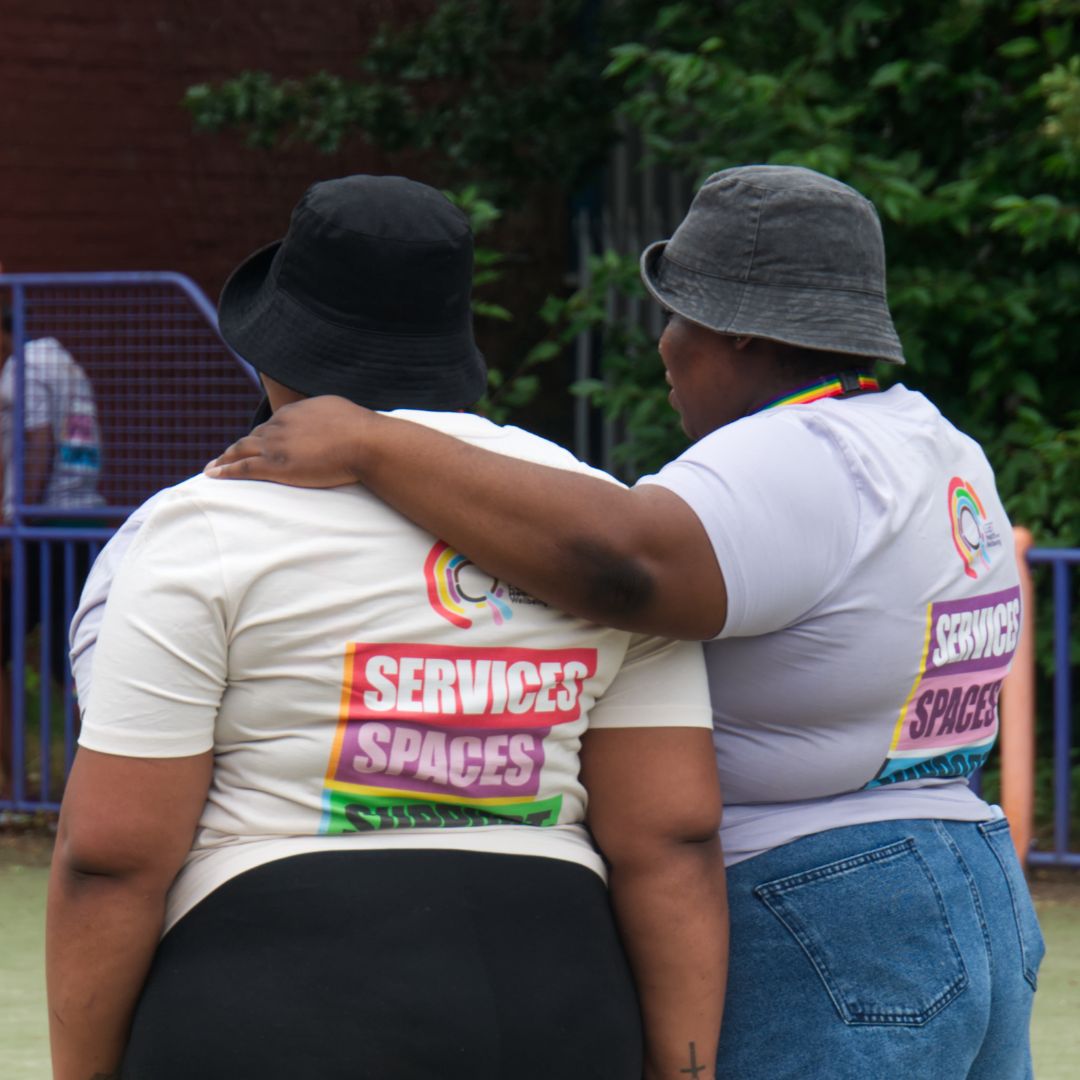 Two community members standing side by side, with one volunteer's arm around the other's shoulder.