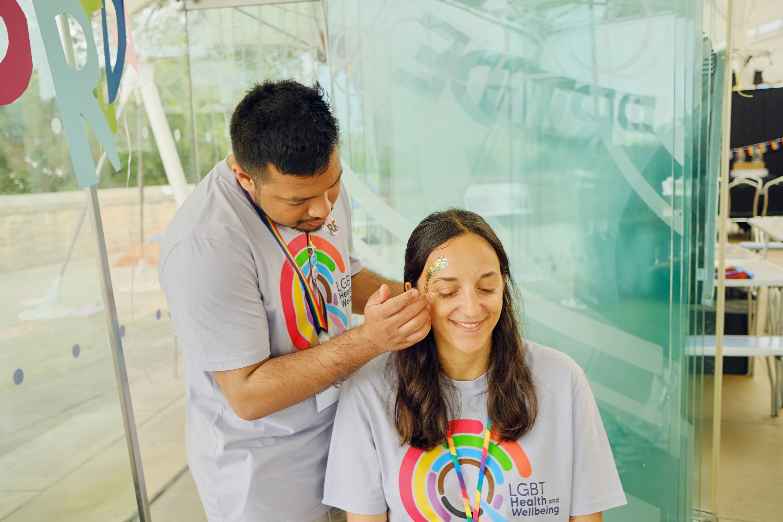 Two LGBT Health and Wellbeing volunteers at our Pride Breakfast event wearing logo t-shirts